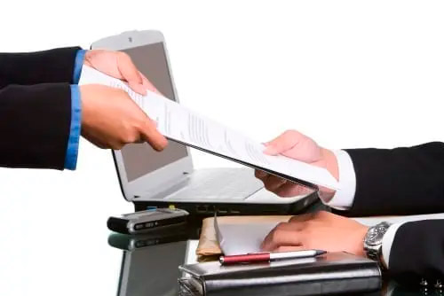 man handing a document to another man
