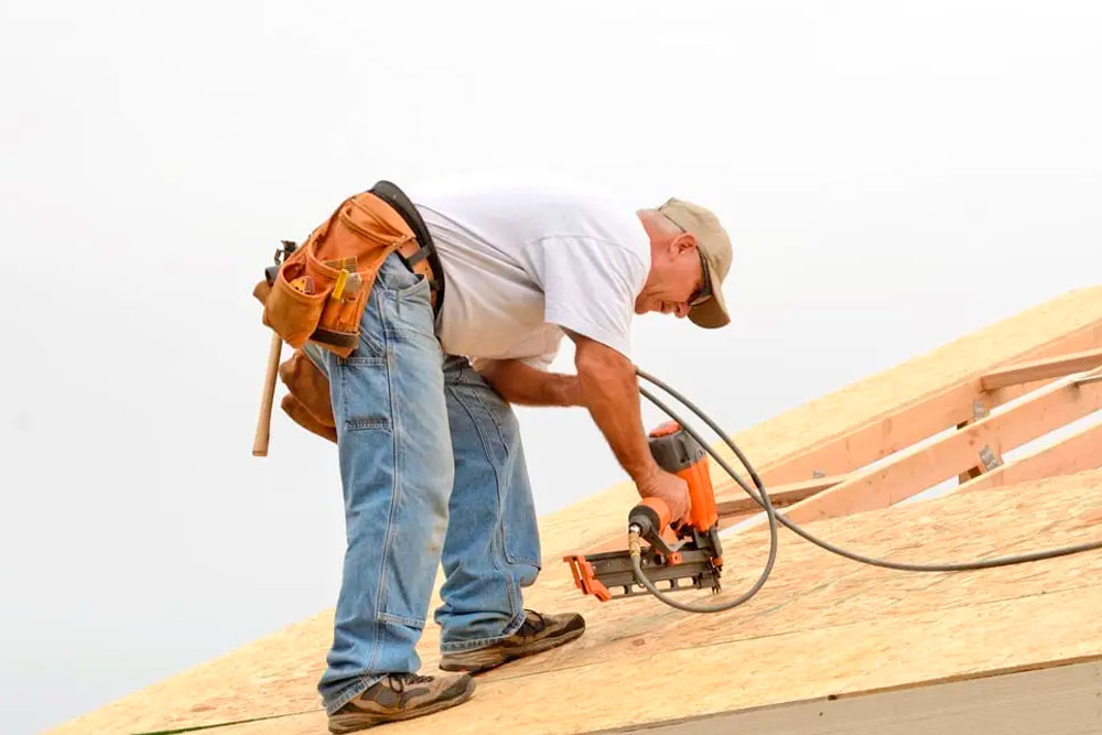 Roofer nailing a sheet to a roof who know the Advice on Construction General Liability Insurance Protection