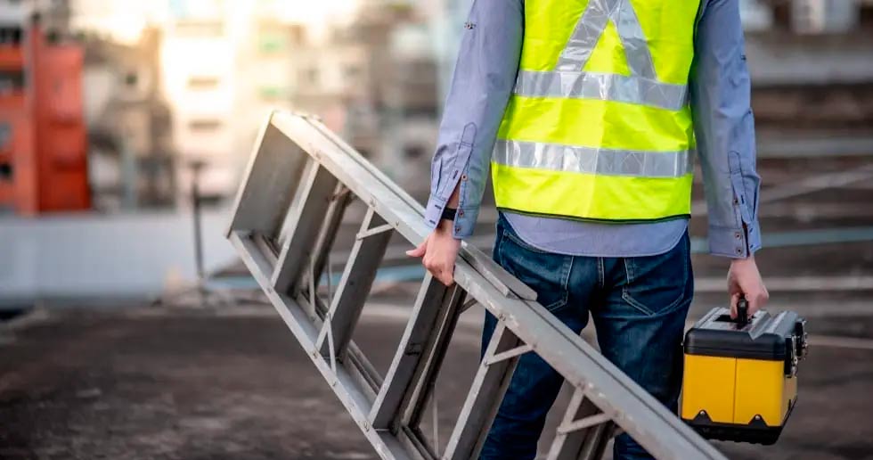 worker carrying a ladder and a tool box